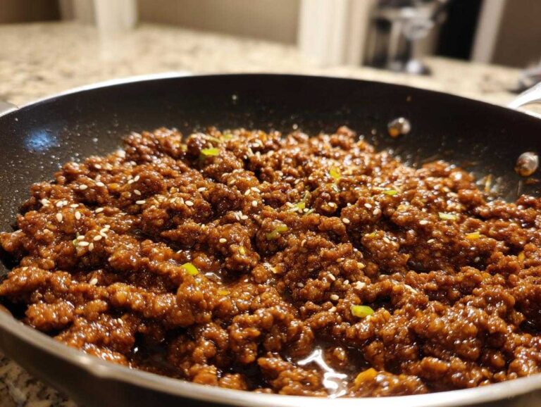 Close-up of ground beef bulgogi in a skillet, garnished with sesame seeds and green onions.