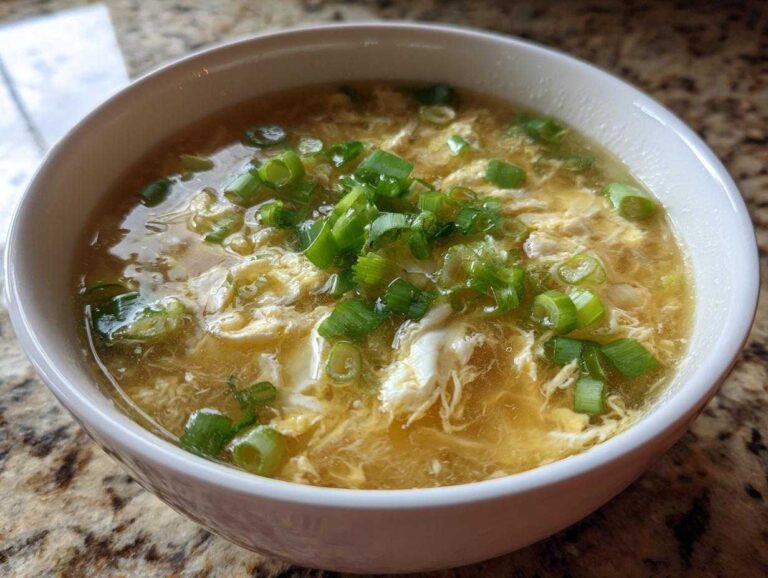 A bowl of steaming egg drop soup, garnished with fresh green onions. Comforting and flavorful egg drop soup.