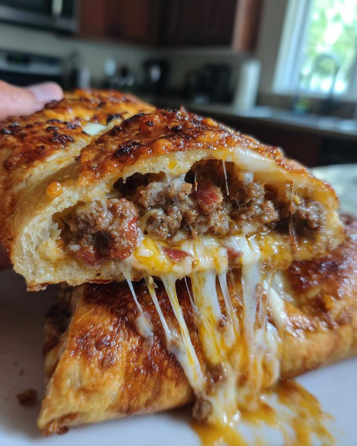 Close-up of a cross-section of garbage bread showing melted, stringy cheese and savory ground meat filling.