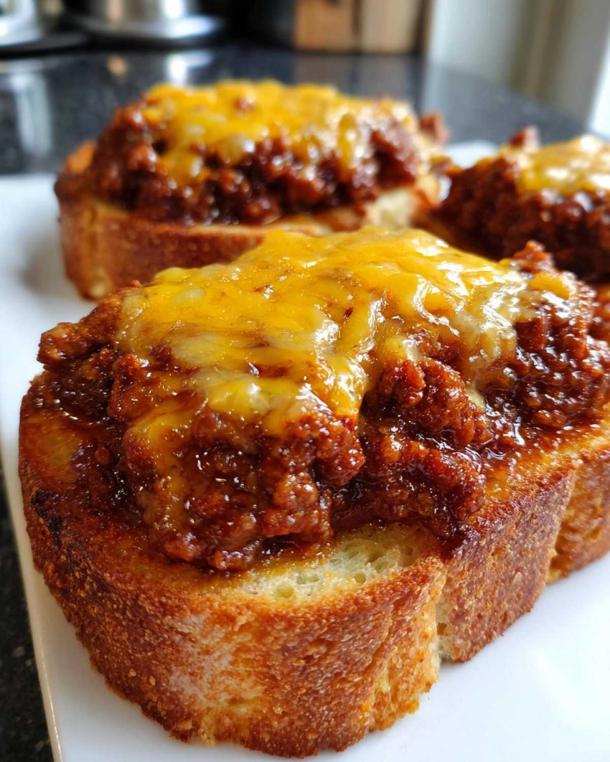 Close-up of cheesy texas toast sloppy joes featuring thick toasted bread topped with savory meat sauce and melted cheddar cheese.