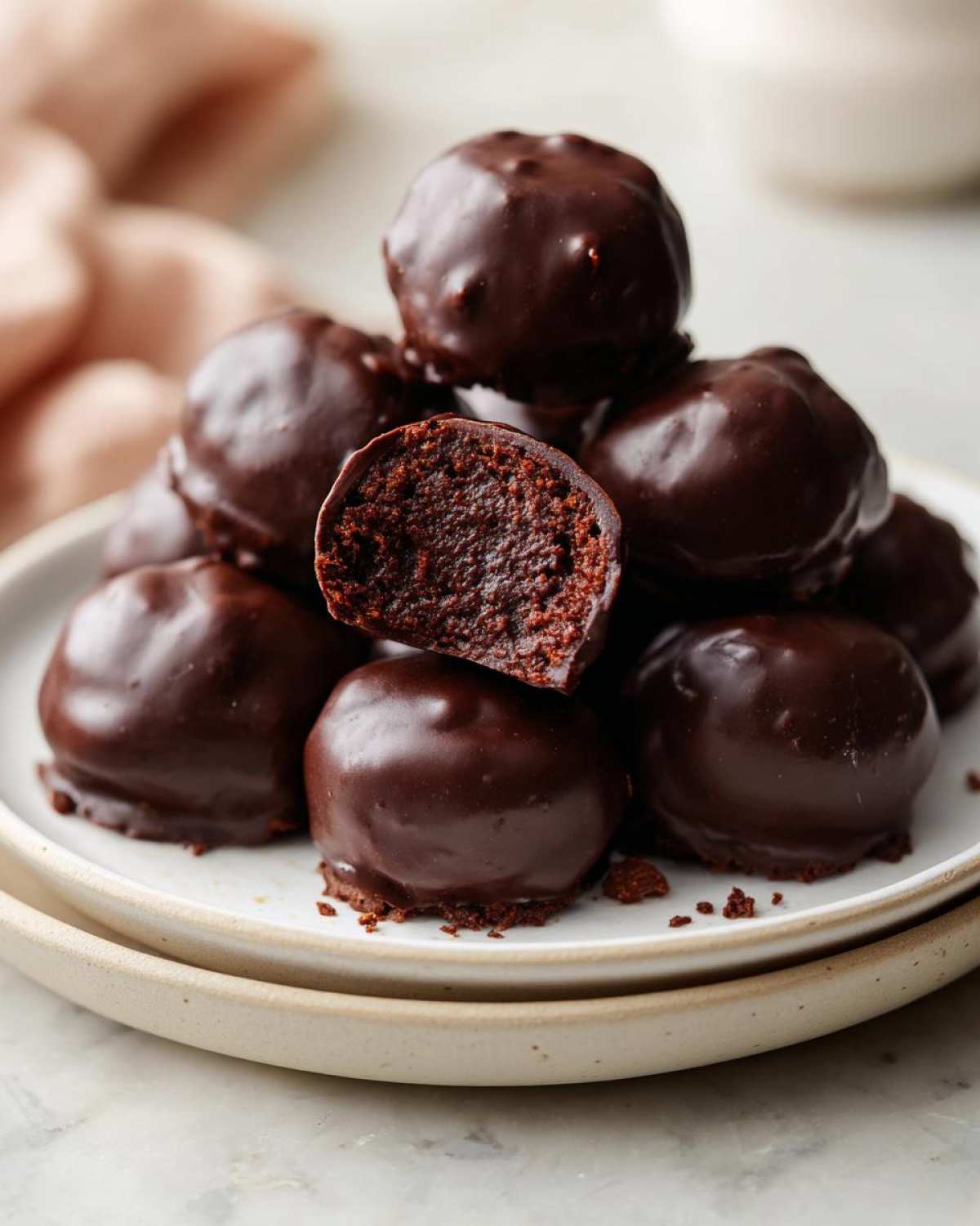 A stack of rich, chocolate-covered pecan pie balls, one cut open to show the dense, dark interior.
