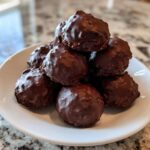 A stack of rich, chocolate-covered pecan pie balls piled high on a small white plate.