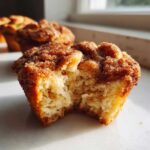 A close-up of a french toast muffins broken in half, showing the soft, fluffy interior and cinnamon-sugar topping.