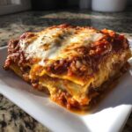 A close-up, appetizing serving of ravioli lasagna covered in rich meat sauce and melted mozzarella cheese.