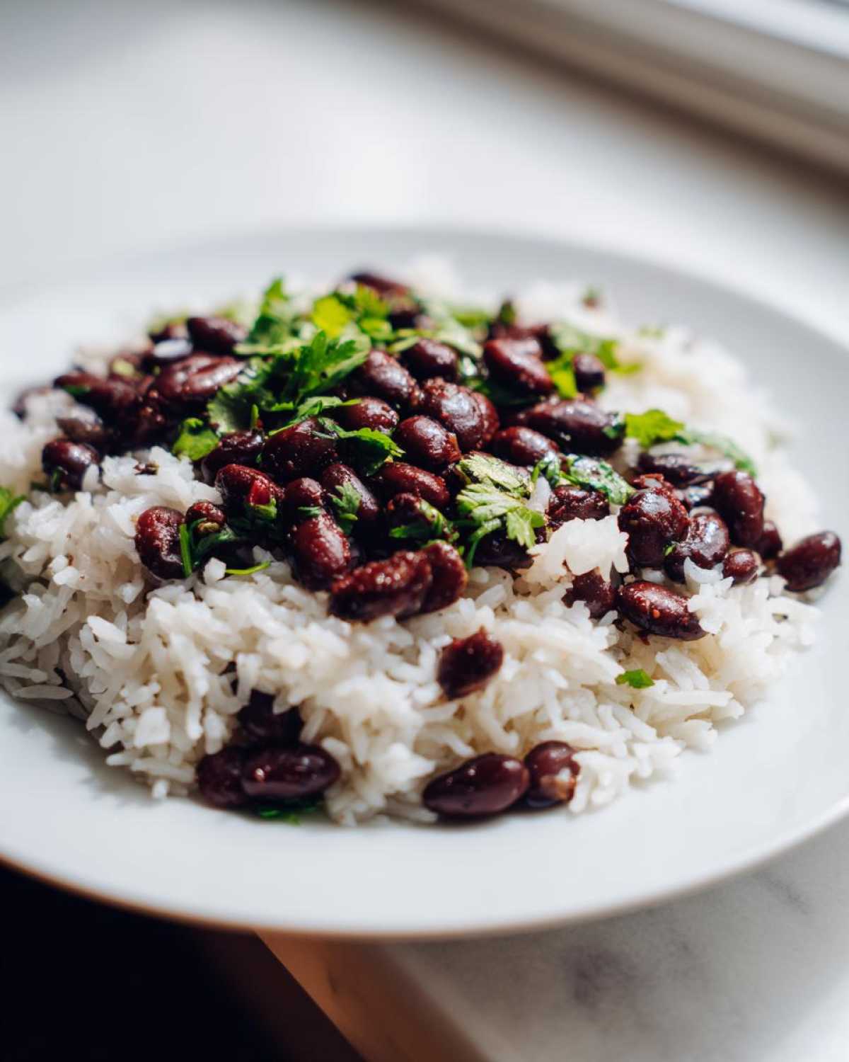 Close-up of fluffy white rice topped generously with seasoned black beans and fresh cilantro.