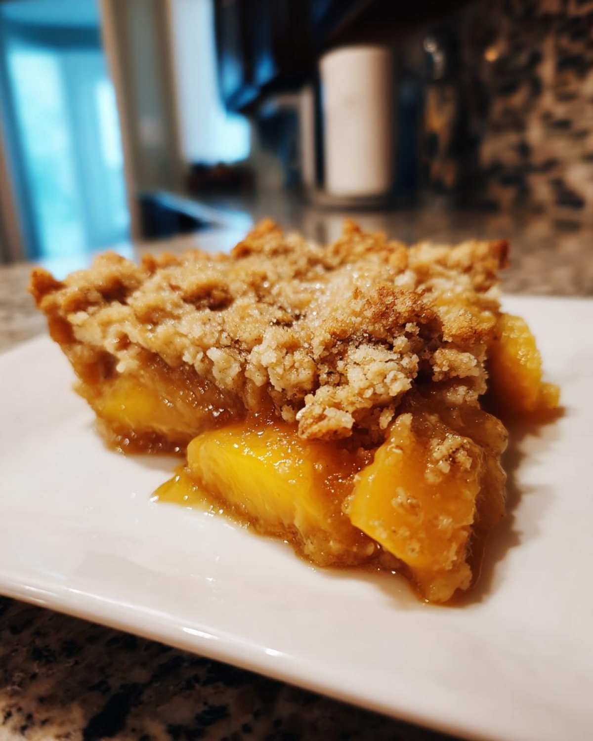 A close-up of a serving of southern peach cobbler with juicy peaches and a golden crumble topping.