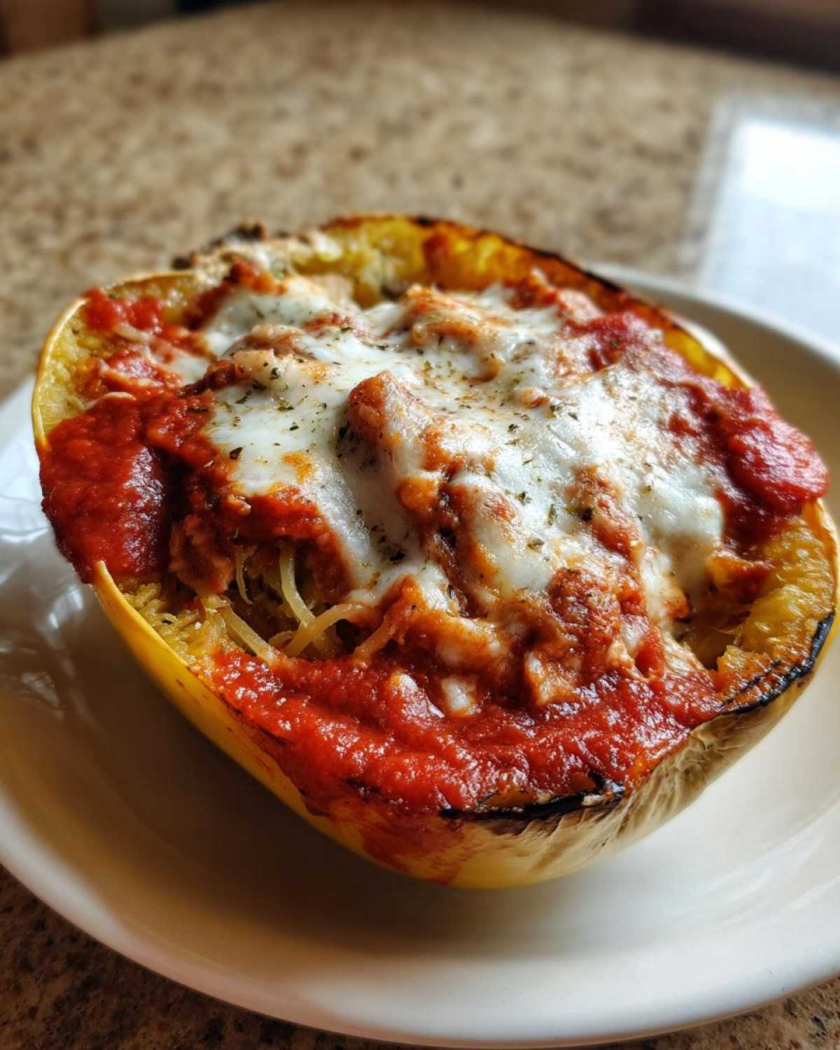 A baked half of spaghetti squash filled with sauce, cheese, and squash strands, representing spaghetti squash lasagna.