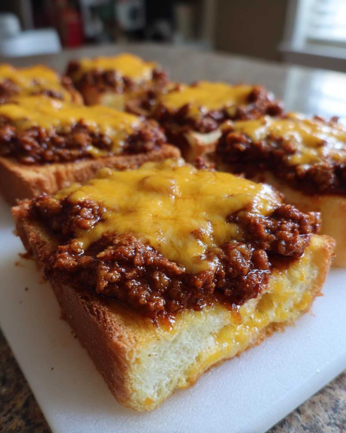 Close-up of several servings of texas toast sloppy joes topped with melted cheddar cheese.