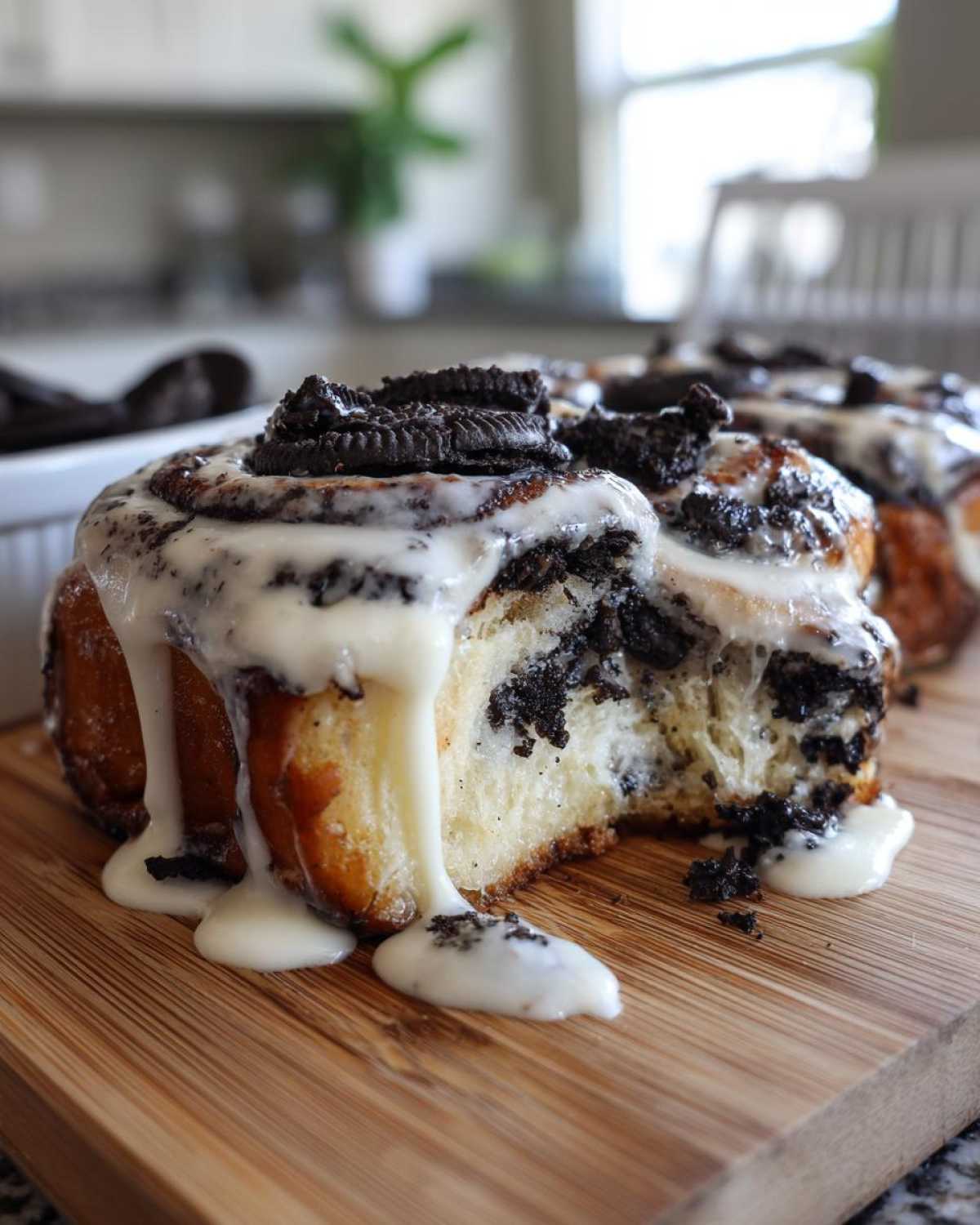 A close-up of a decadent Oreo cinnamon roll, dripping with white icing and topped with crushed Oreo pieces.