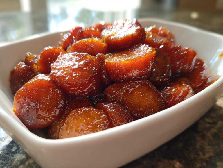 Close-up of glistening, caramelized southern candied yams served in a small white dish.