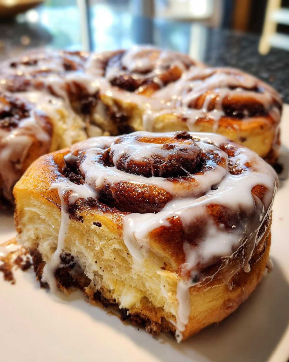 A close-up of a soft, gooey oreo cinnamon roll with white icing dripping down the side.
