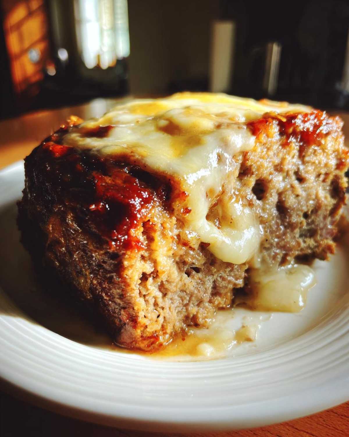 Close-up of a moist slice of crockpot French onion meatloaf topped with melted Swiss cheese.