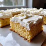 A thick, square slice of light yellow sugar cookie bars topped with generous white frosting.