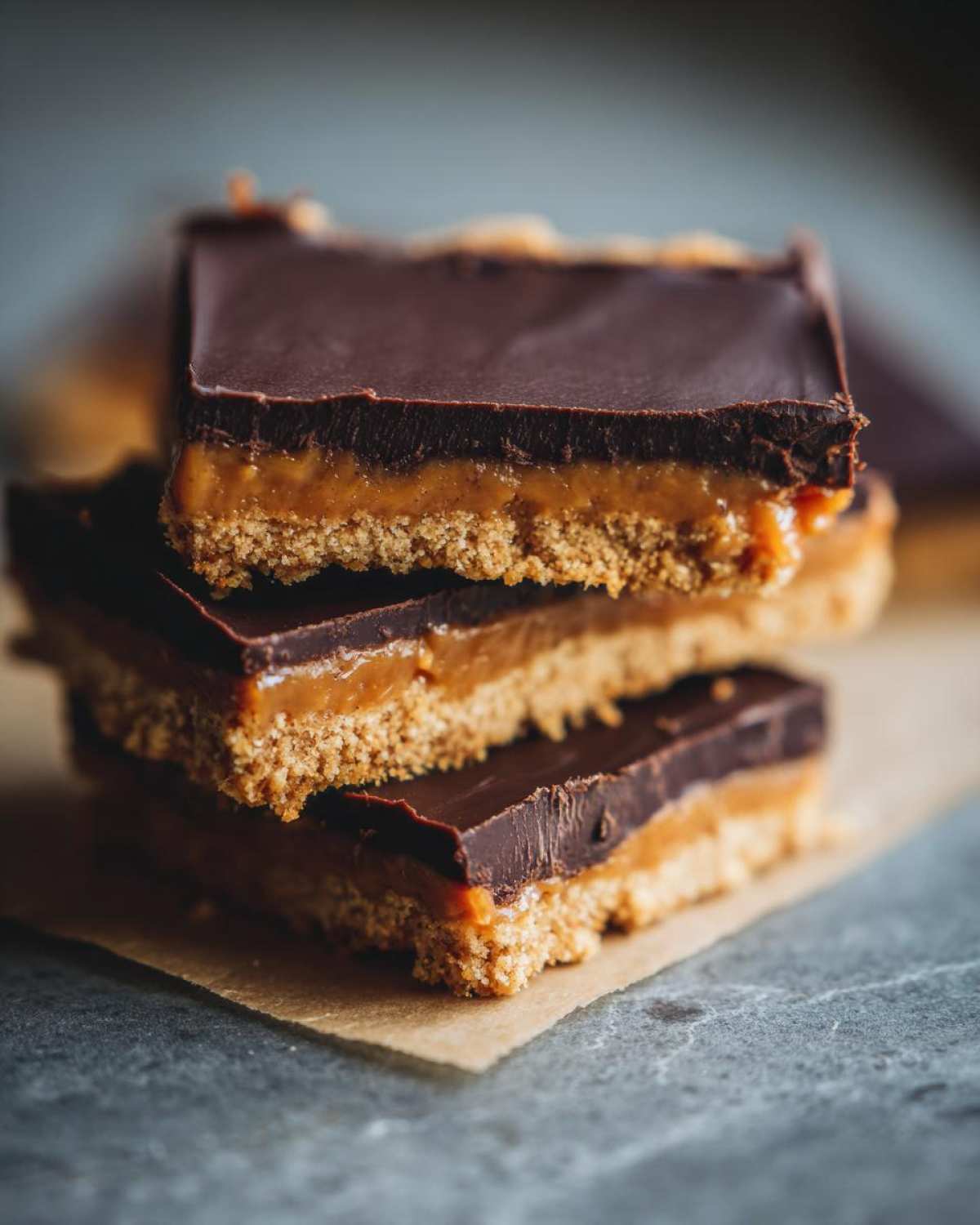 A stack of three rich graham cracker toffee bars with a thick chocolate top layer.