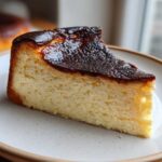 A close-up slice of creamy Basque burnt cheesecake with a dark, caramelized top.