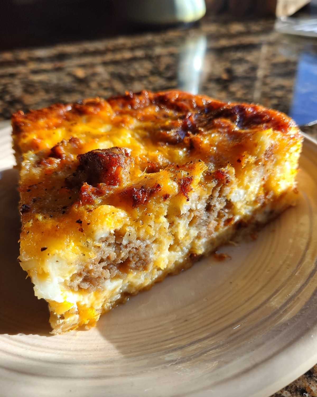 A close-up slice of savory Christmas breakfast casserole featuring sausage and a golden, cheesy top.