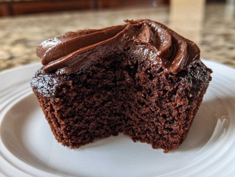 A close-up view showing the moist, fudgy interior texture of a chocolate cupcake with rich chocolate frosting.