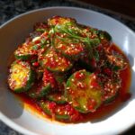 Close-up of vibrant Korean cucumber salad tossed in spicy red chili flakes and sesame seeds.