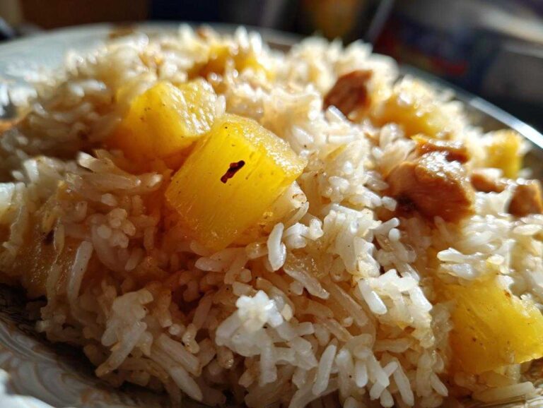 Close-up of fluffy white rice mixed with chunks of golden pineapple and pieces of chicken from the pineapple chicken and rice recipe.
