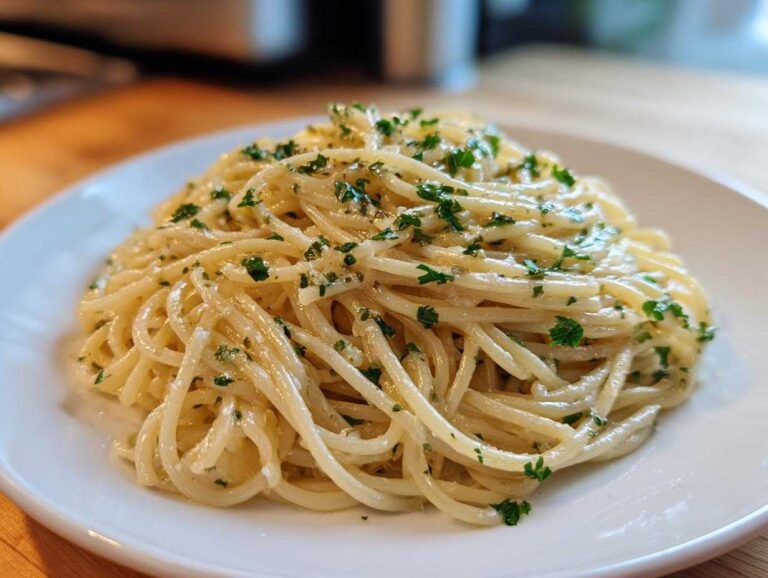 A close-up of perfectly coated spaghetti noodles making up a serving of garlic butter pasta, garnished with fresh parsley.