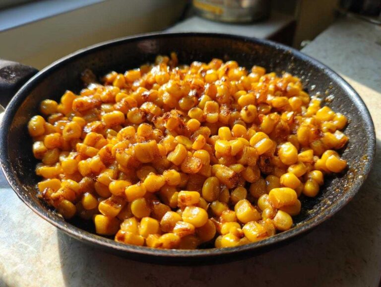 Close-up of bright yellow, caramelized honey butter skillet corn sizzling in a dark non-stick pan.