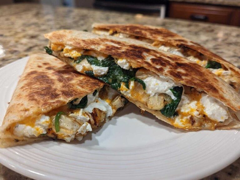 Three wedges of golden-brown mediterranean quesadillas filled with white cheese, spinach, and roasted vegetables, served on a white plate.