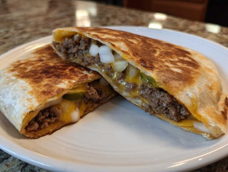 Two halves of a golden-brown smashburger quesadillas filled with seasoned ground beef, melted cheddar cheese, pickles, and diced white onions.