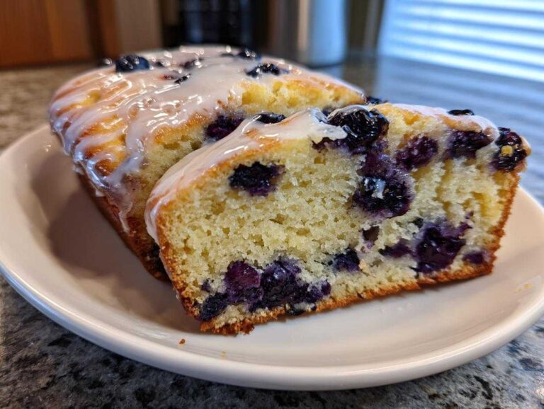 Close-up of a slice of Blueberry lemon blondies with citrus glaze, showing moist crumb and burst blueberries.