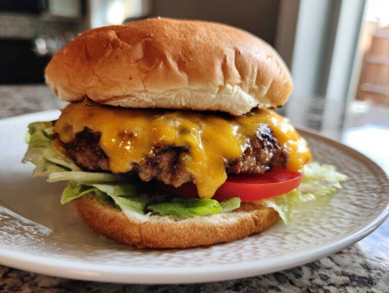 A close-up of a juicy classic burger with 80/20 ground chuck, melted cheddar cheese, lettuce, and tomato on a bun.
