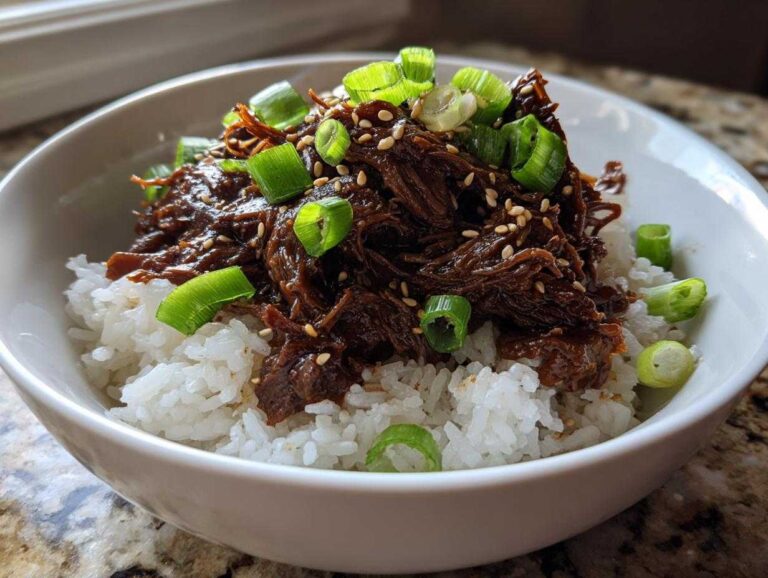A close-up of tender Korean beef slow cooker bowls served over white rice and topped with green onions and sesame seeds.